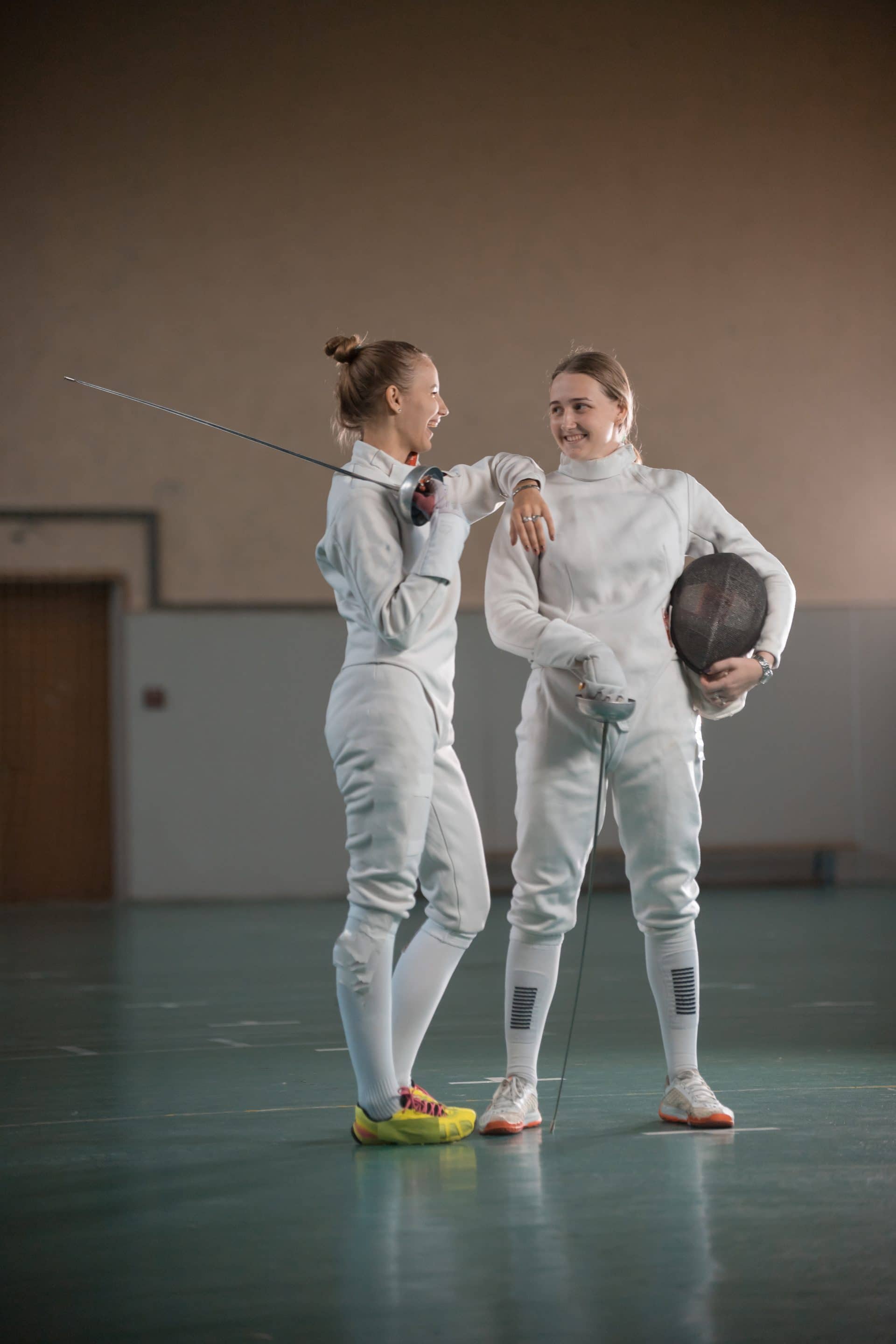 A portrait of two young women fencers laughing
